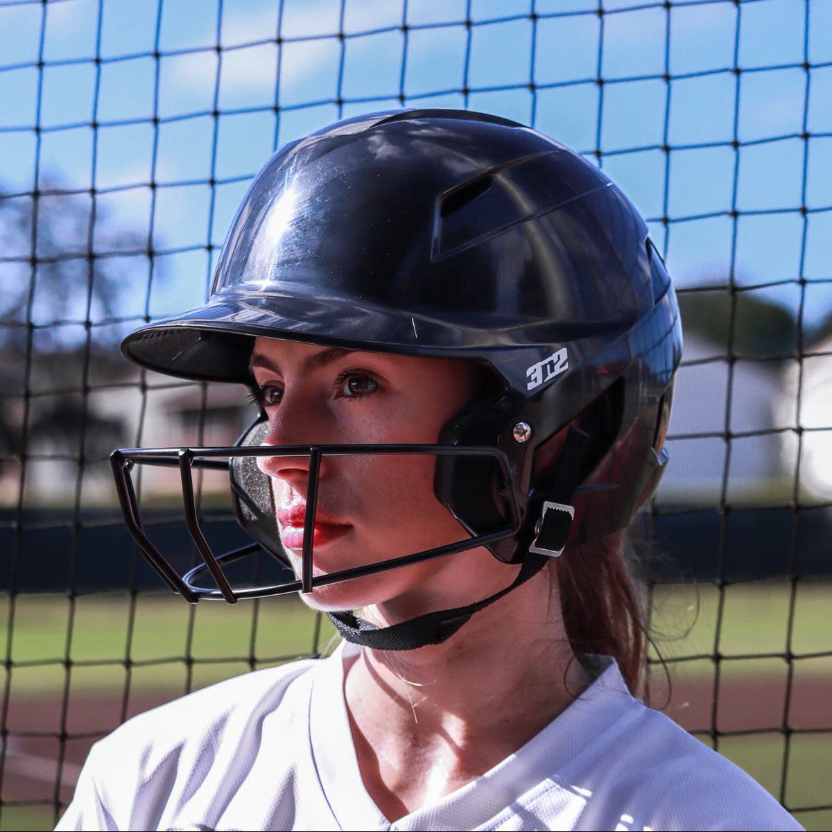 Person wearing a black helmet and white jersey with 'St. Louis' text, standing in front of a netted background.